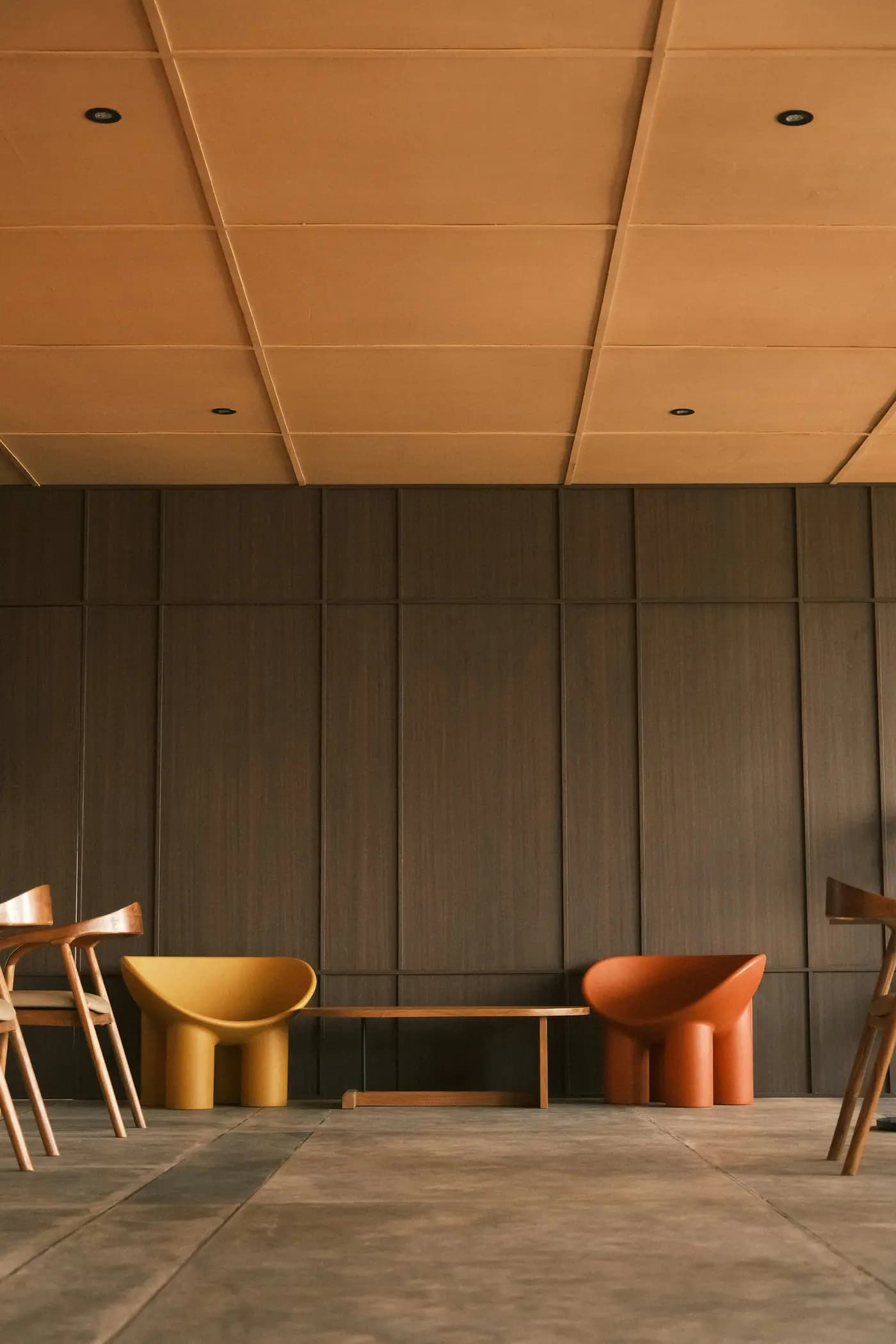 Minimalist seating area with sculptural chairs and wooden walls.